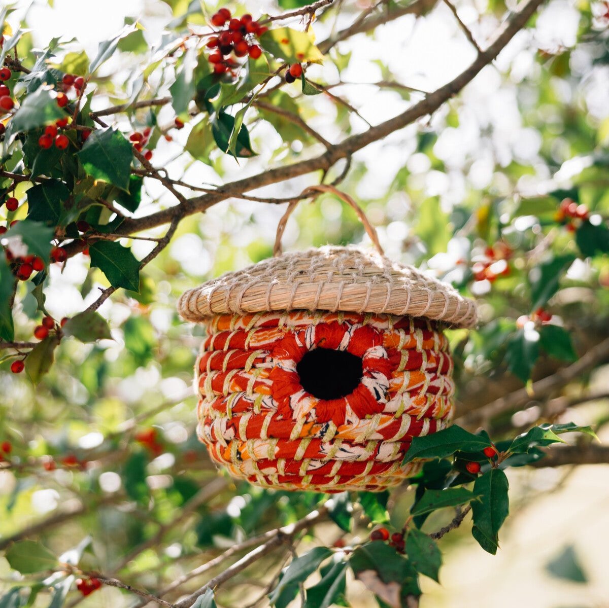 Birdhouse hanging in a garden with small birds flying nearby