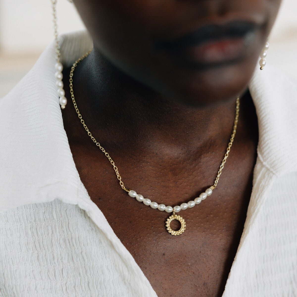 Close-up of the Golden Artisan Pearl Charm Necklace showcasing its unique sunburst charm and pearls.