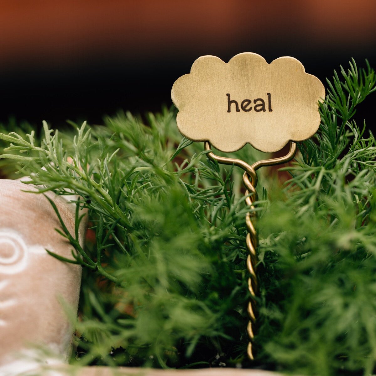 Person inserting a handcrafted plant marker into a potted plant for labeling