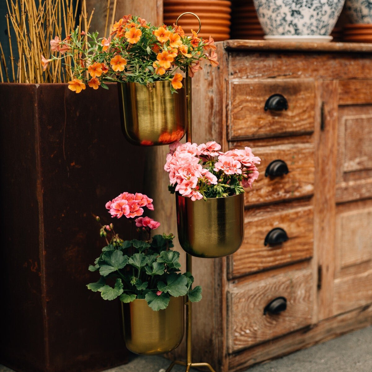 Elegant tiered brass plant stand with lush indoor plants in a bright living room.