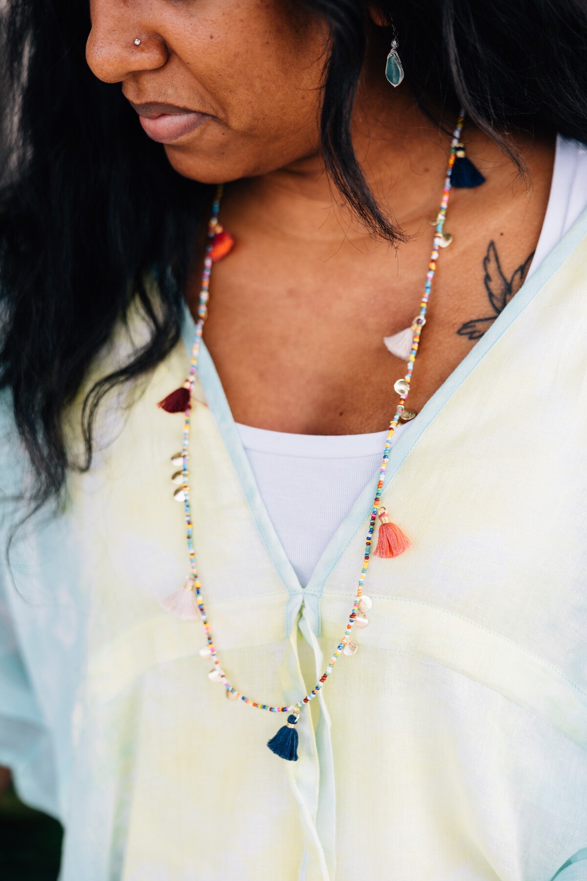 Close-up of artisan-crafted gold beaded tassel disc necklace with intricate details