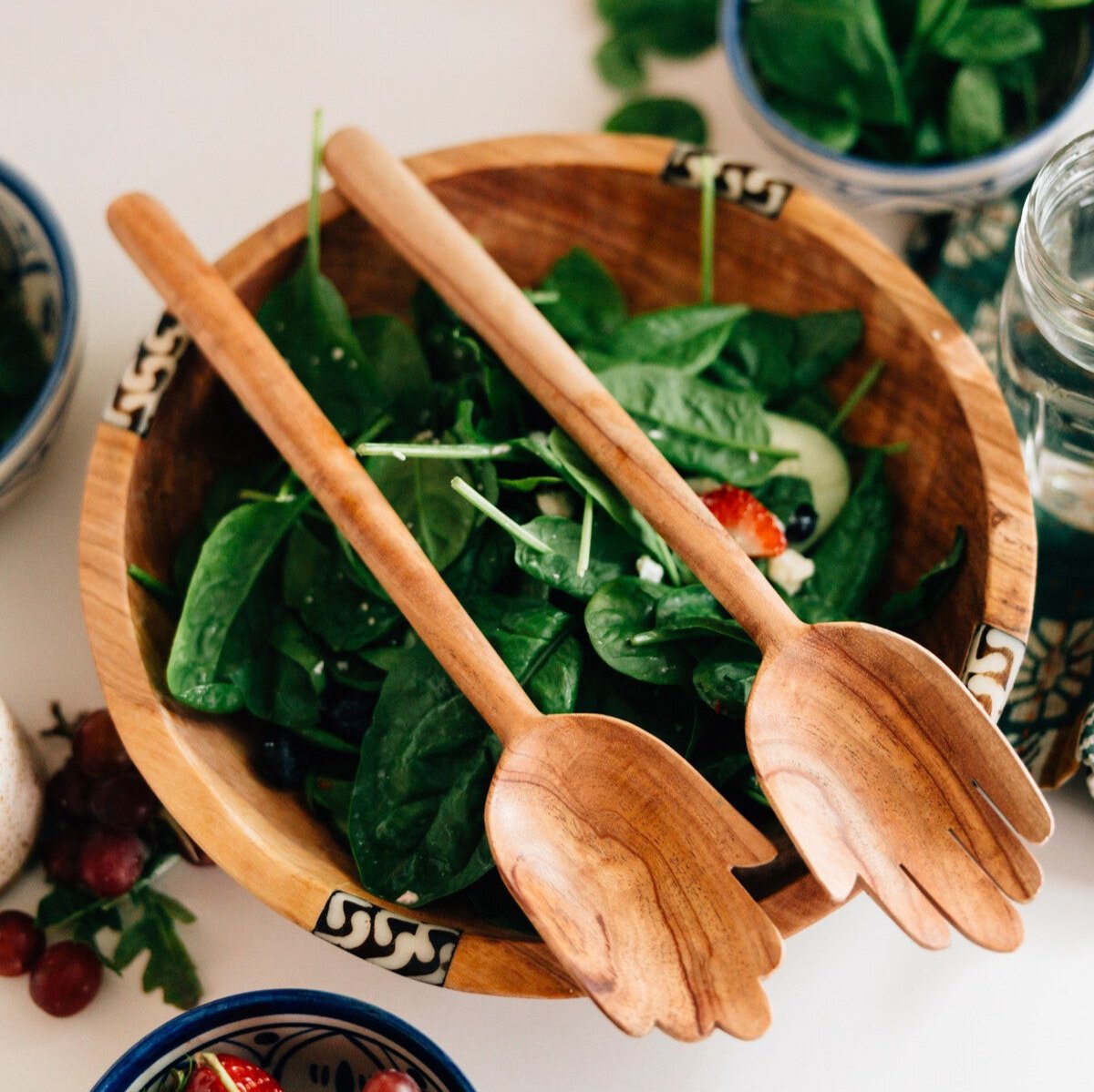Olive wood bowl filled with a fresh salad on a beautifully set dining table.