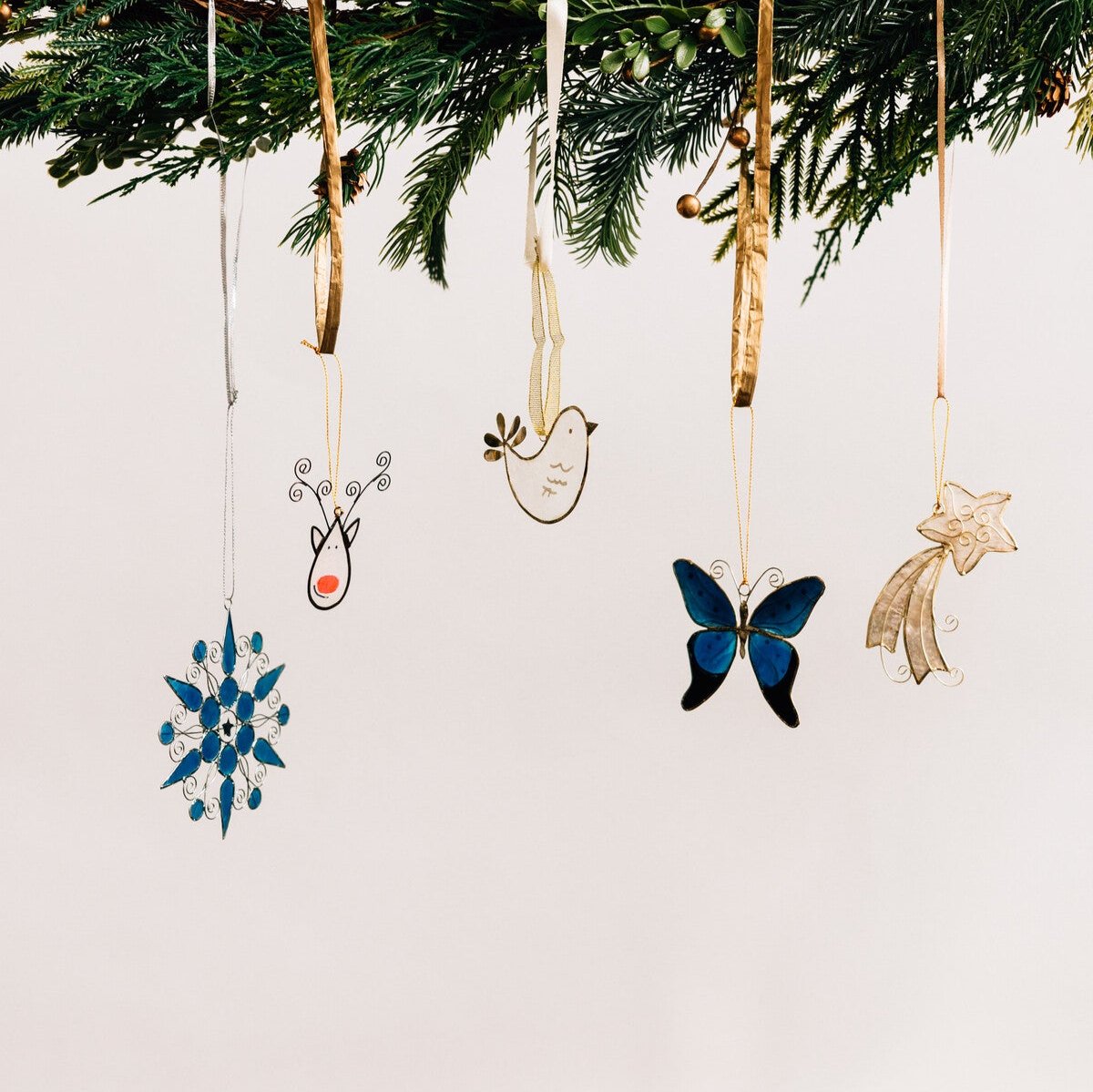 Artisan-made shooting star ornament styled with other holiday ornaments for a festive, elegant look.