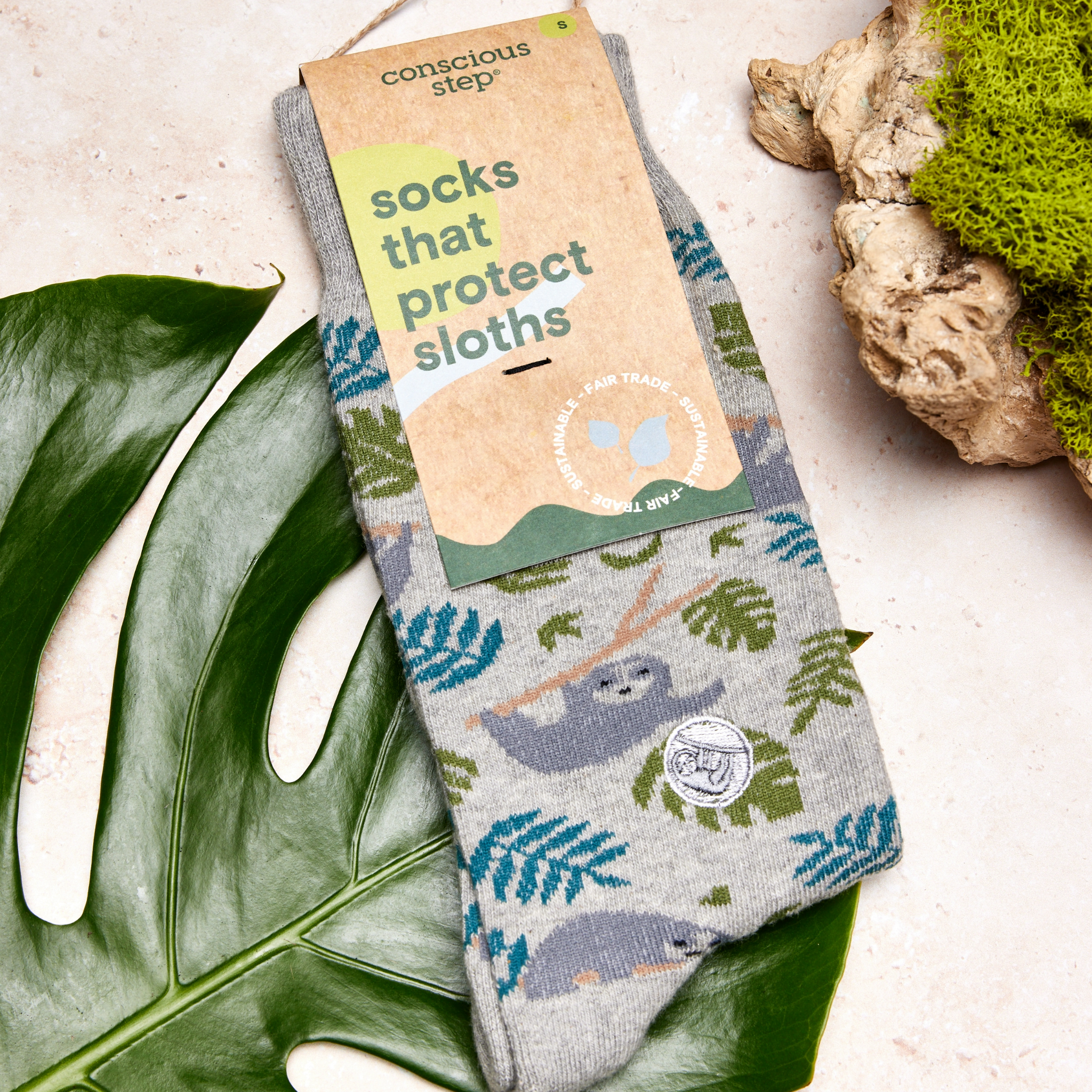 Comfortable socks that help save sloths, displayed on a wooden surface.