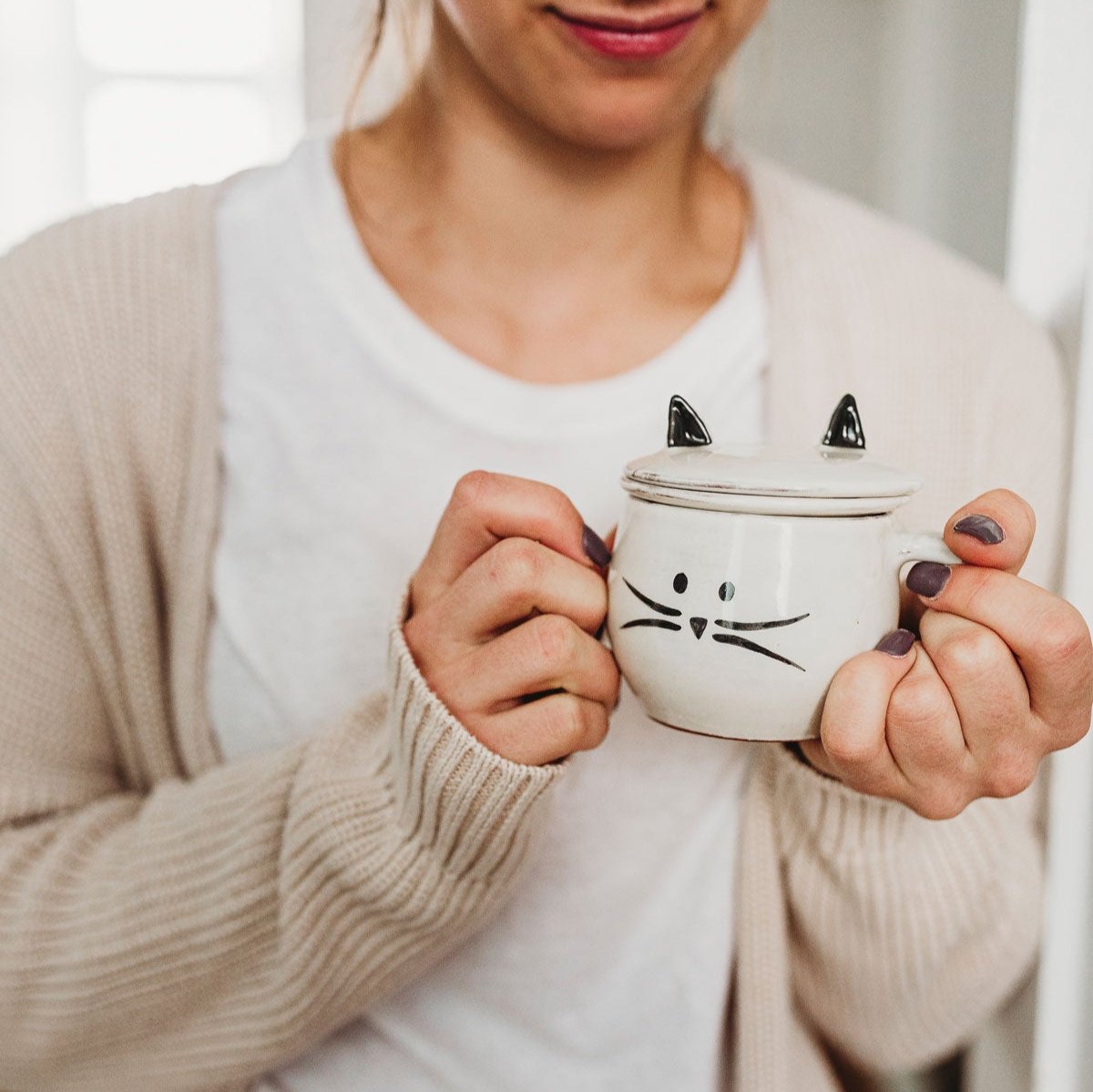 Close-up view of the ceramic mug featuring a cute cat face and removable lid