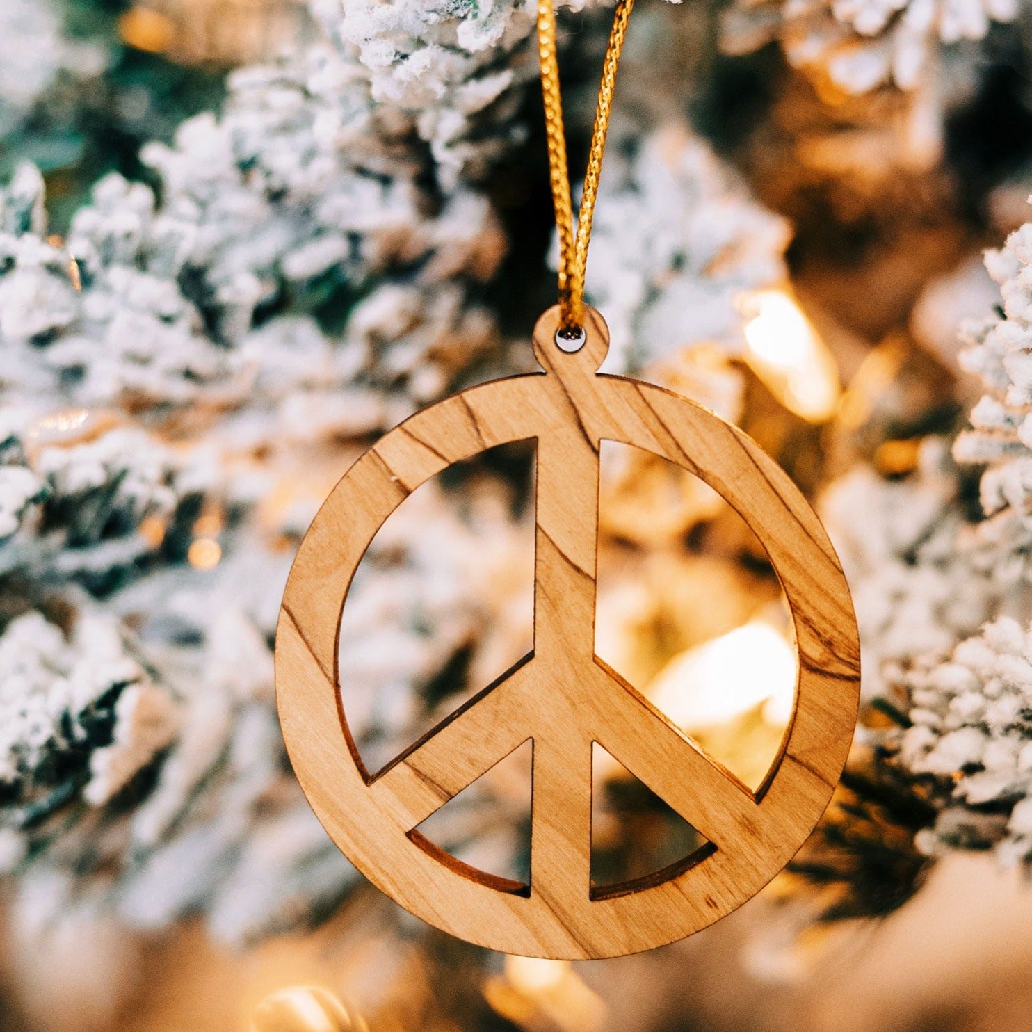 Olive wood Christmas ornament with peace symbol, showcasing its intricate design.