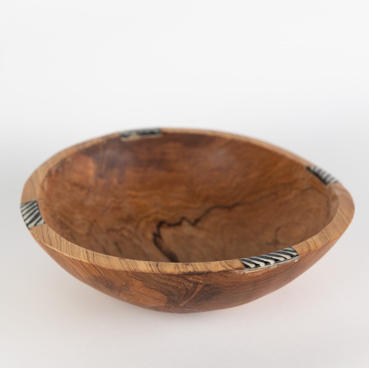 Side view of an artisan olive wood serving bowl showcasing its unique grain and bone inlay.