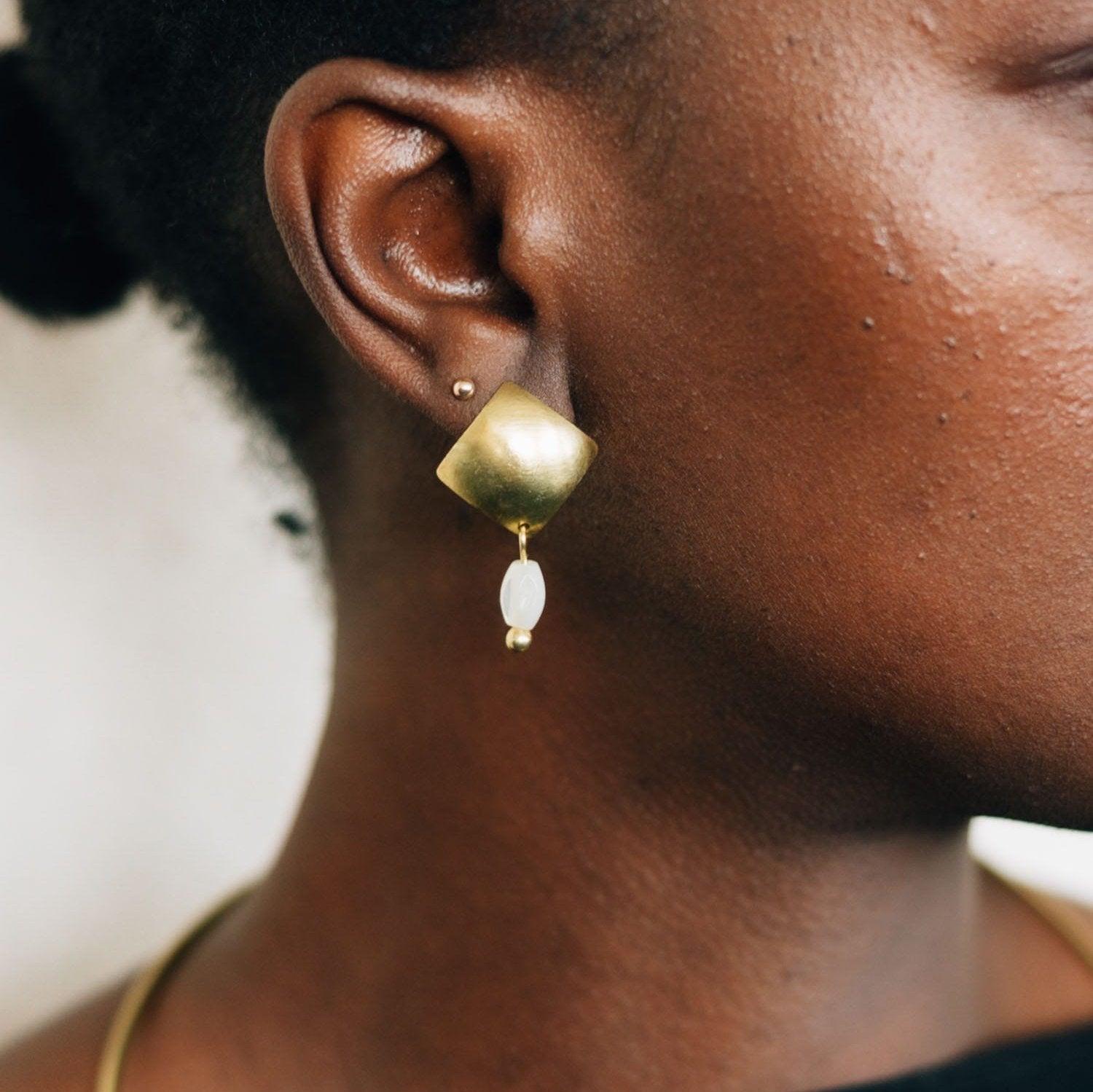 Side view of handmade bead drop earrings with mother-of-pearl beads and gold finish