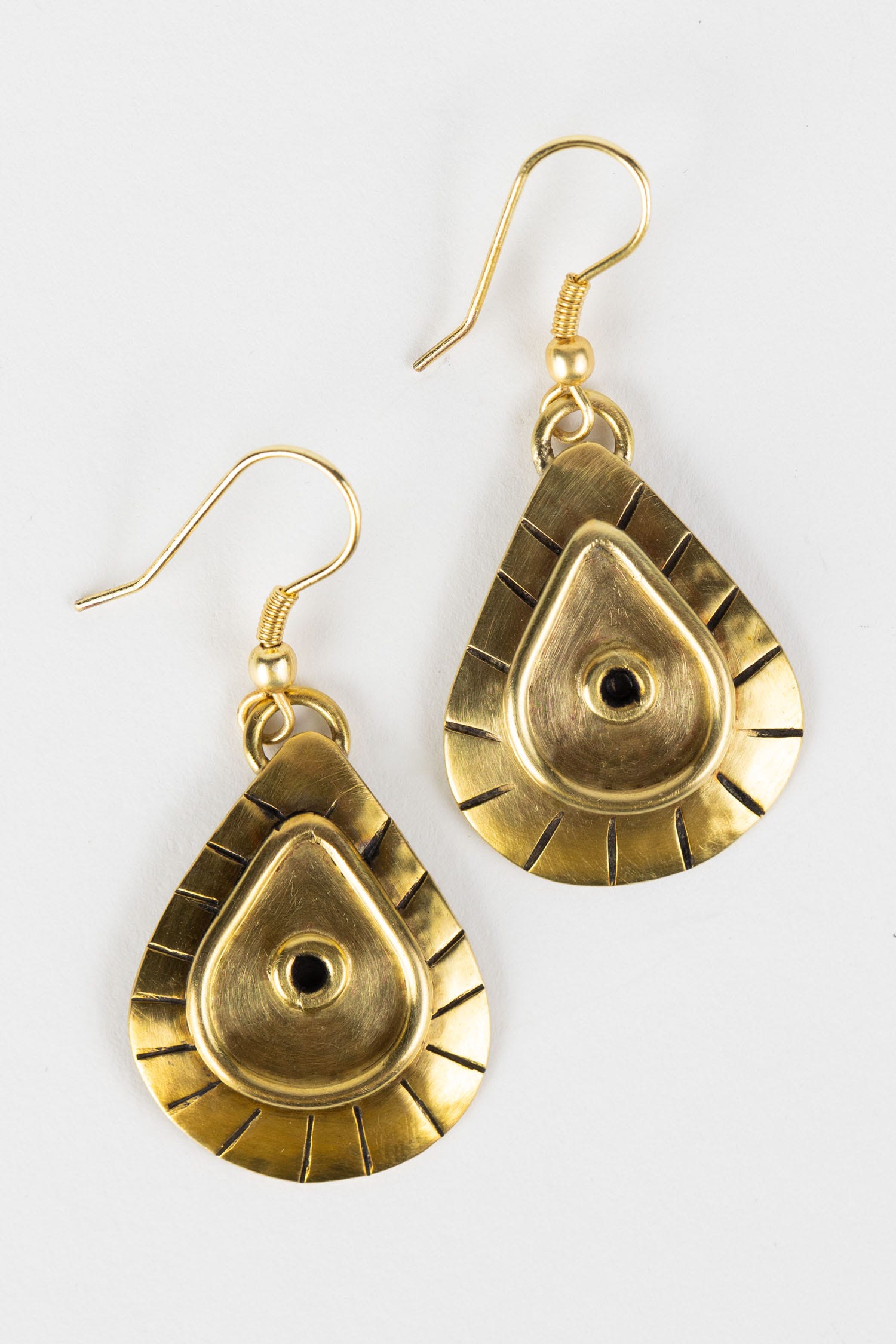 Close-up of handcrafted brass drop earrings showcasing tribal design