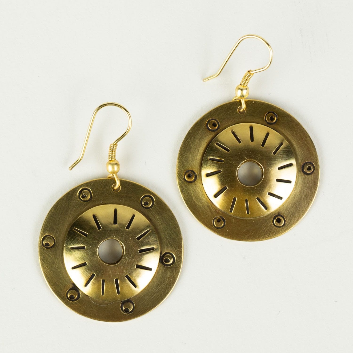 Close-up of brass shield earrings showing detailed craftsmanship