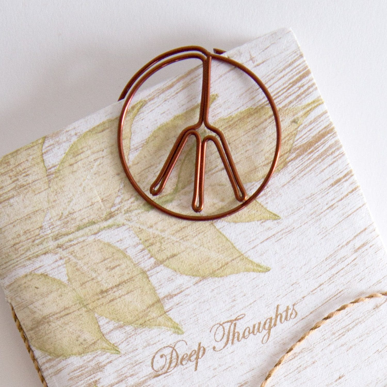 Close-up of the Tranquil Lake Bookmark on an open novel, showing handmade texture and natural tones.