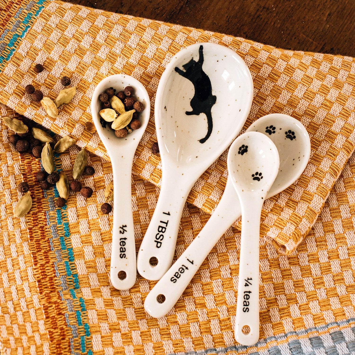 Close-up of hand-painted cat-themed measuring spoons lying on kitchen countertop