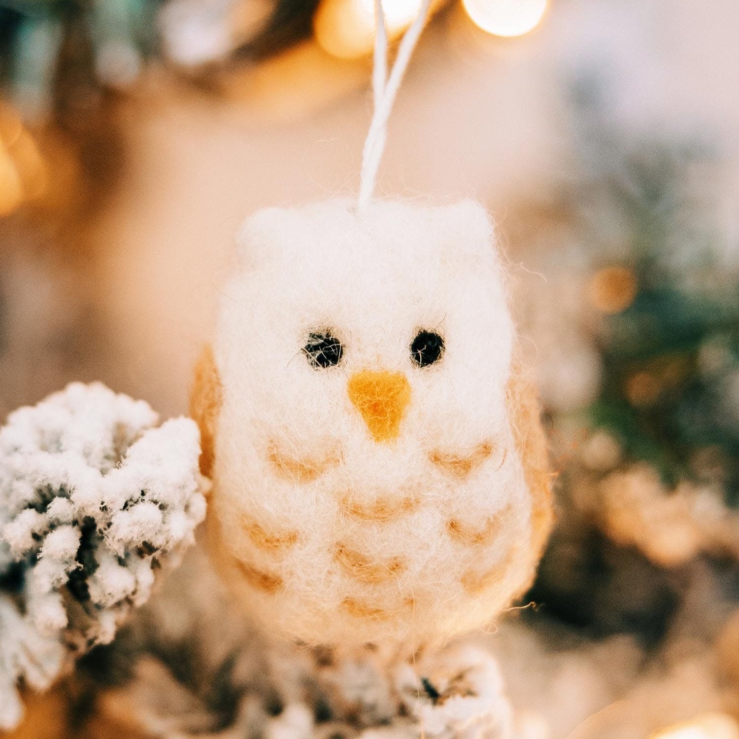 Felted owl ornament hanging on a festive Christmas tree, showcasing handcrafted wool details