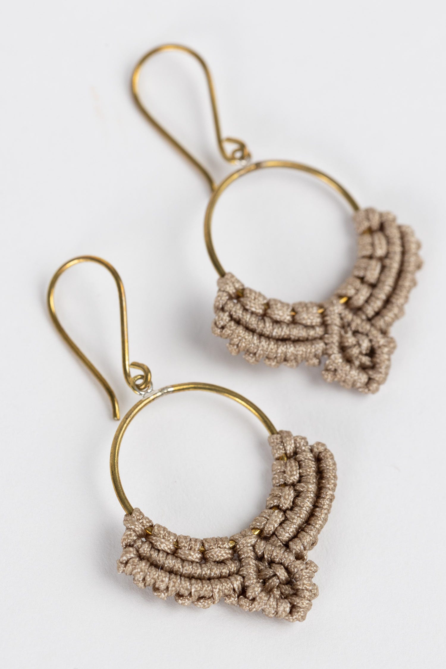 Handmade macrame dew drop earrings with brass hoops on a natural background