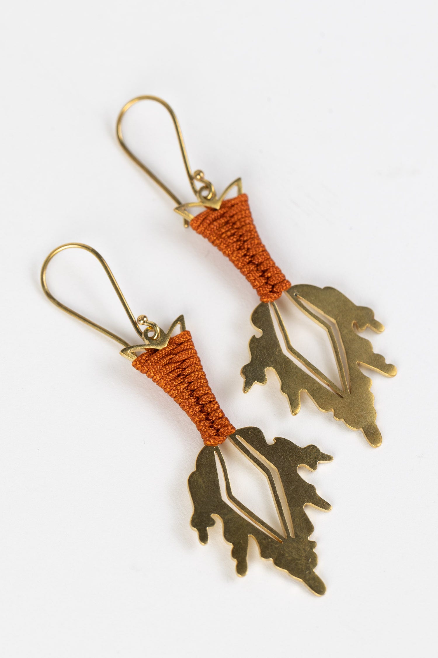 Close-up of handcrafted brass fire spear earrings with fiery cording detail