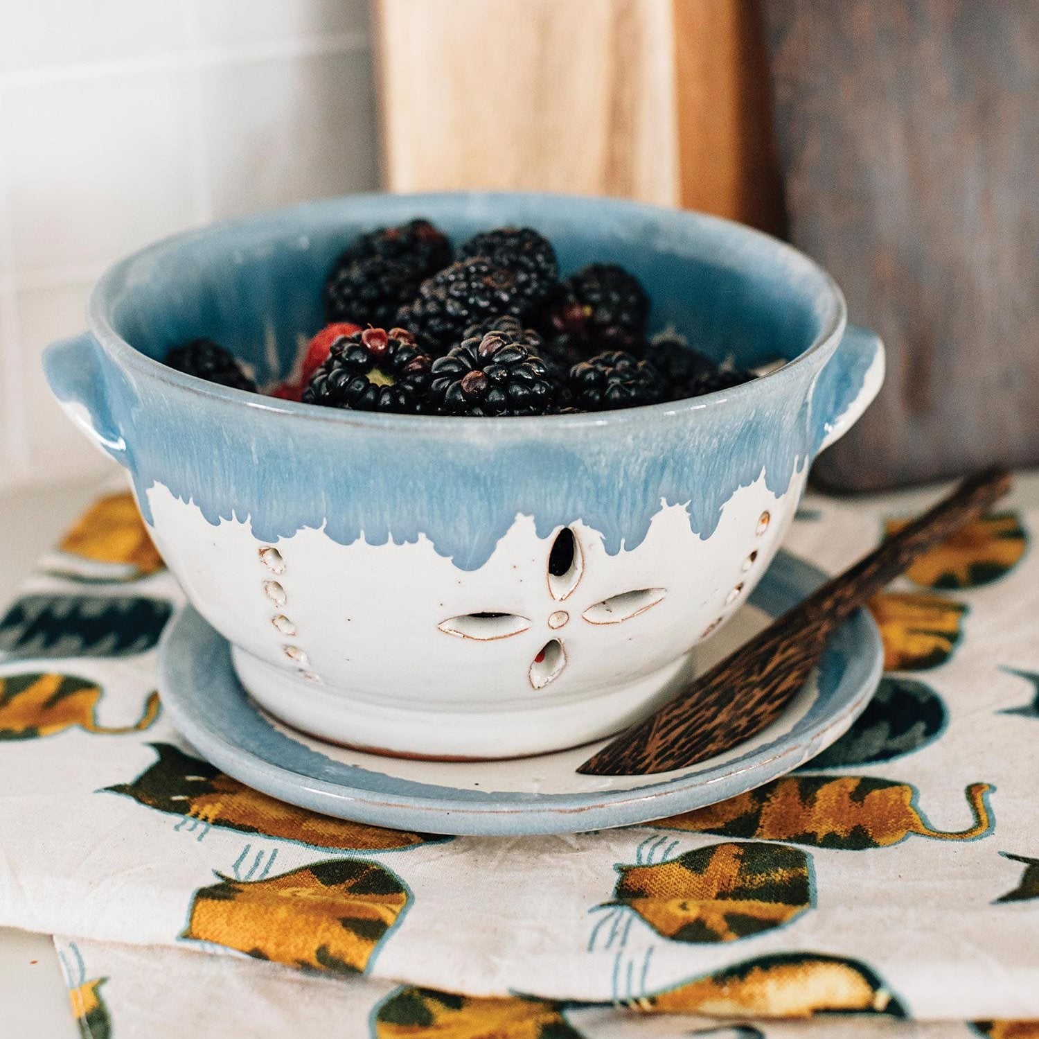 Ceramic fruit bowl with strainer for berries in use on kitchen countertop