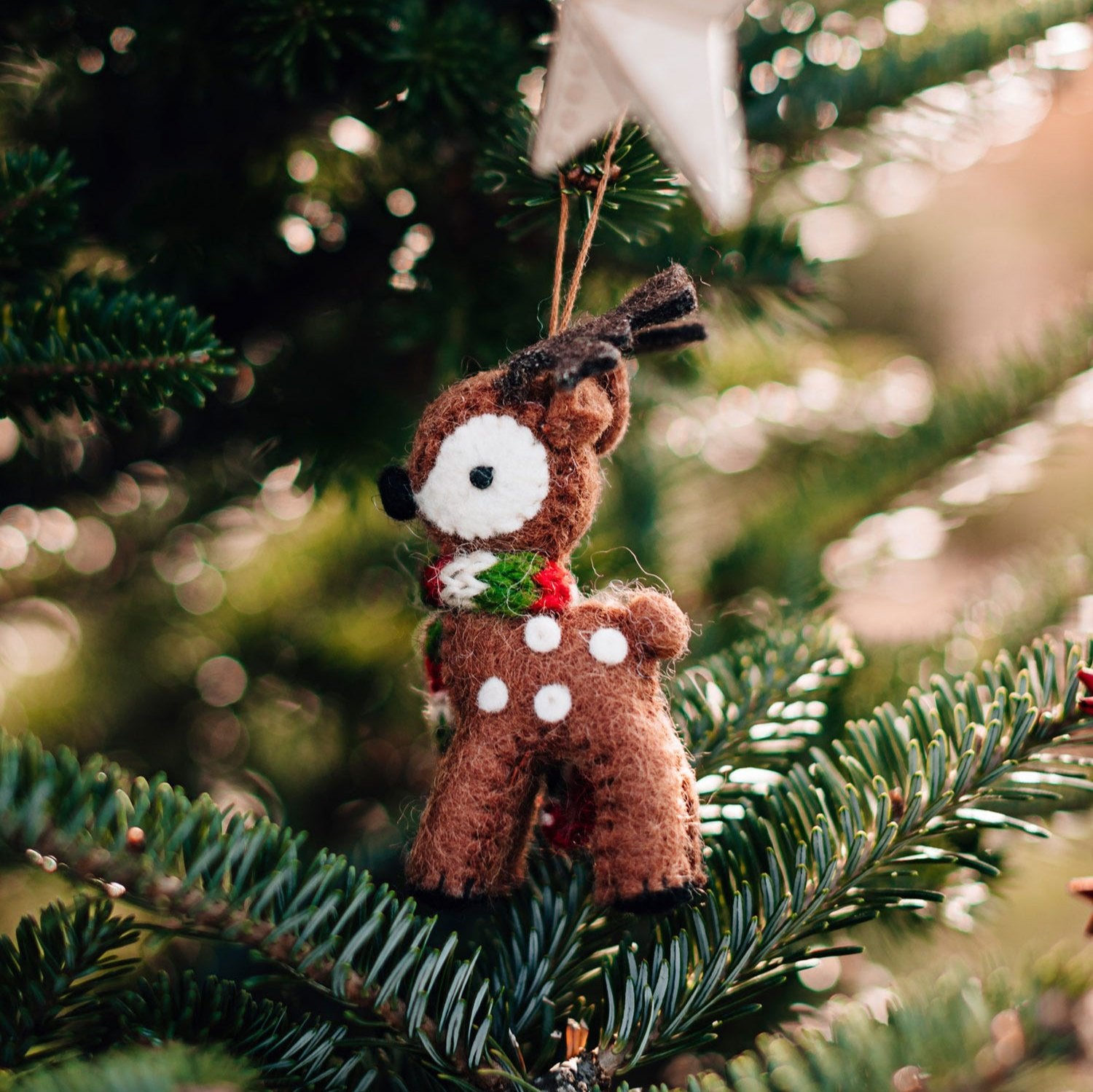Artisan handmade reindeer ornament hanging on a Christmas tree, bringing a festive touch to the decorations.
