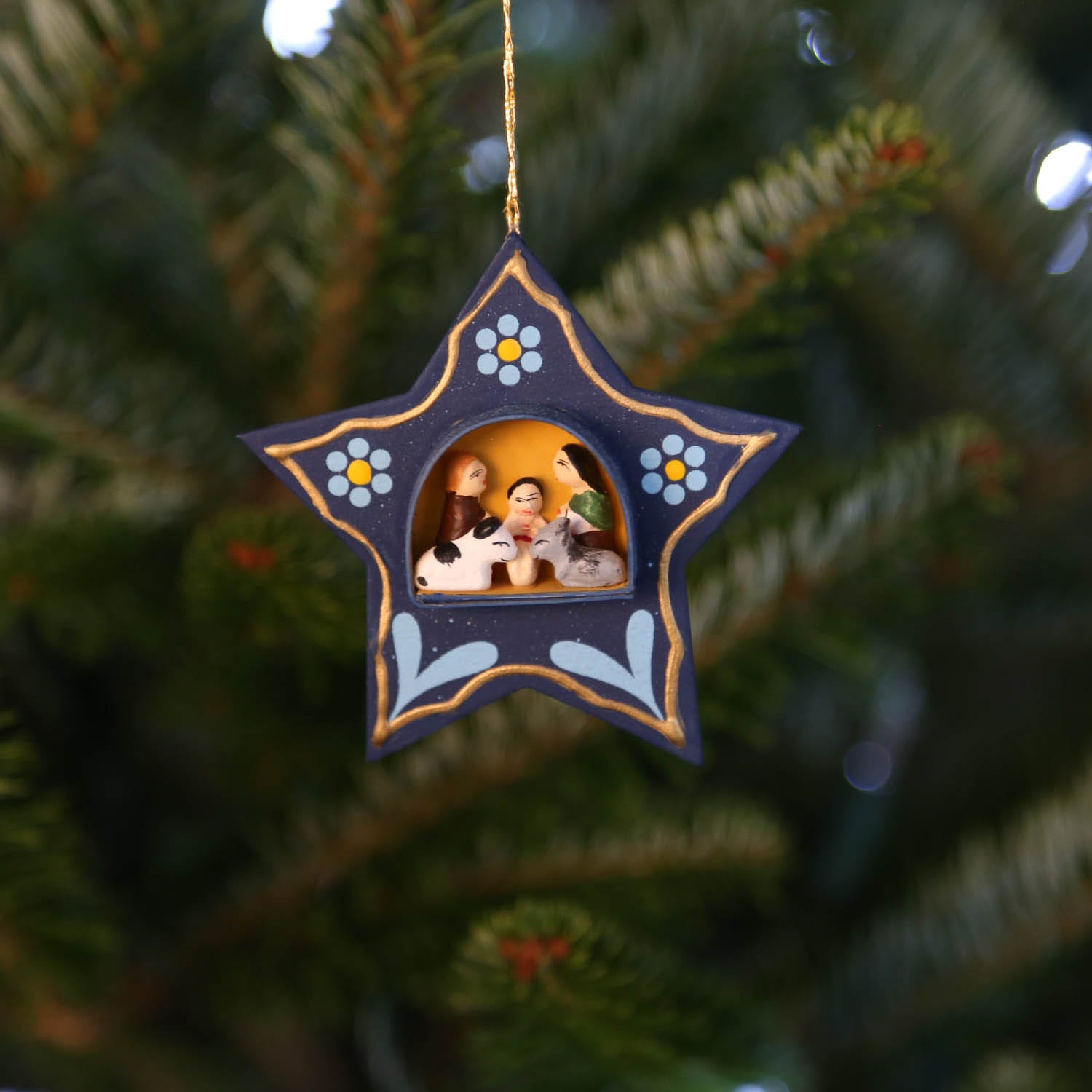 Front view of a miniature nativity star ornament showcasing the intricate retablo design.