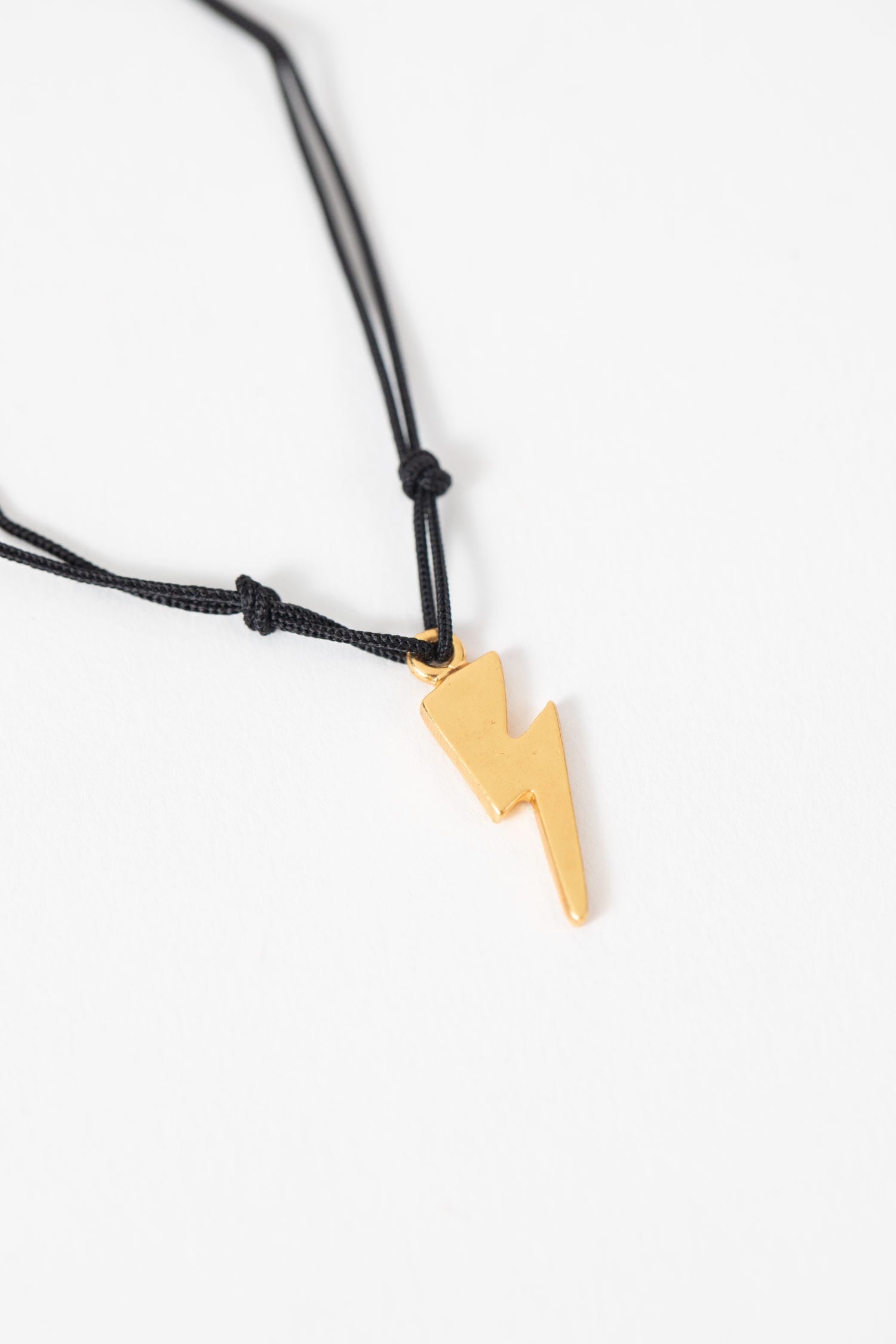 Close-up of the Creative Spark Lightning Bolt Bracelet showcasing the 24K gold charm and black nylon cord.