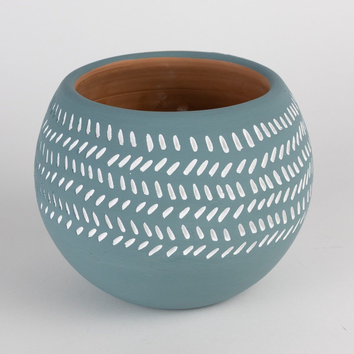 Close-up of handcrafted teal geometric terracotta planter with subtle pattern