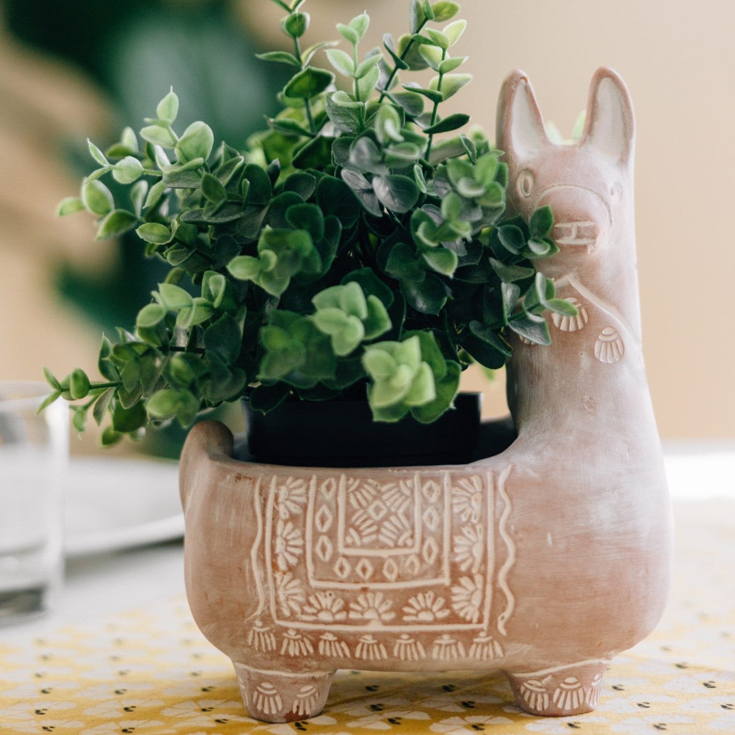 Front view of handcrafted llama terracotta planter styled with succulents on a wooden shelf