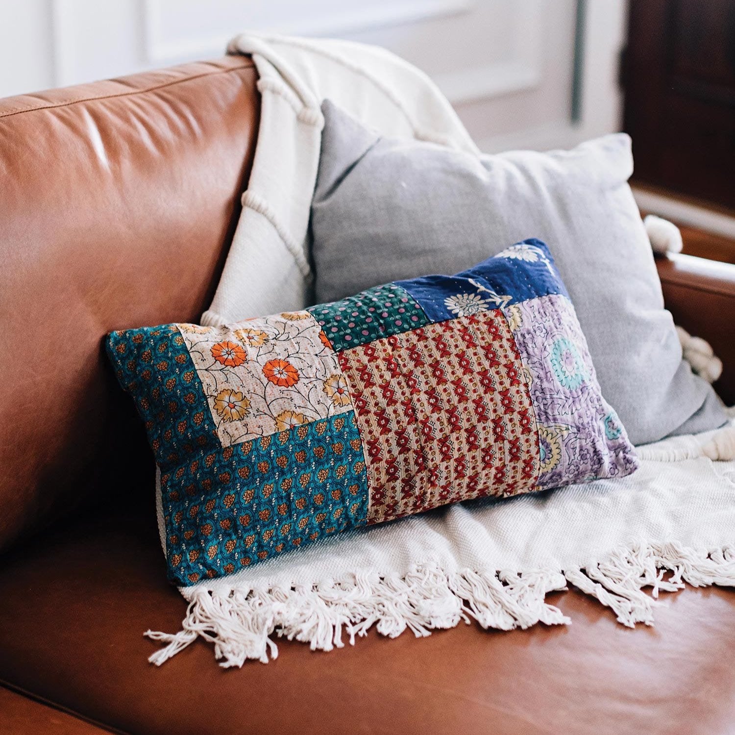 Bright patchwork sari cushion with coconut shell buttons on a sofa