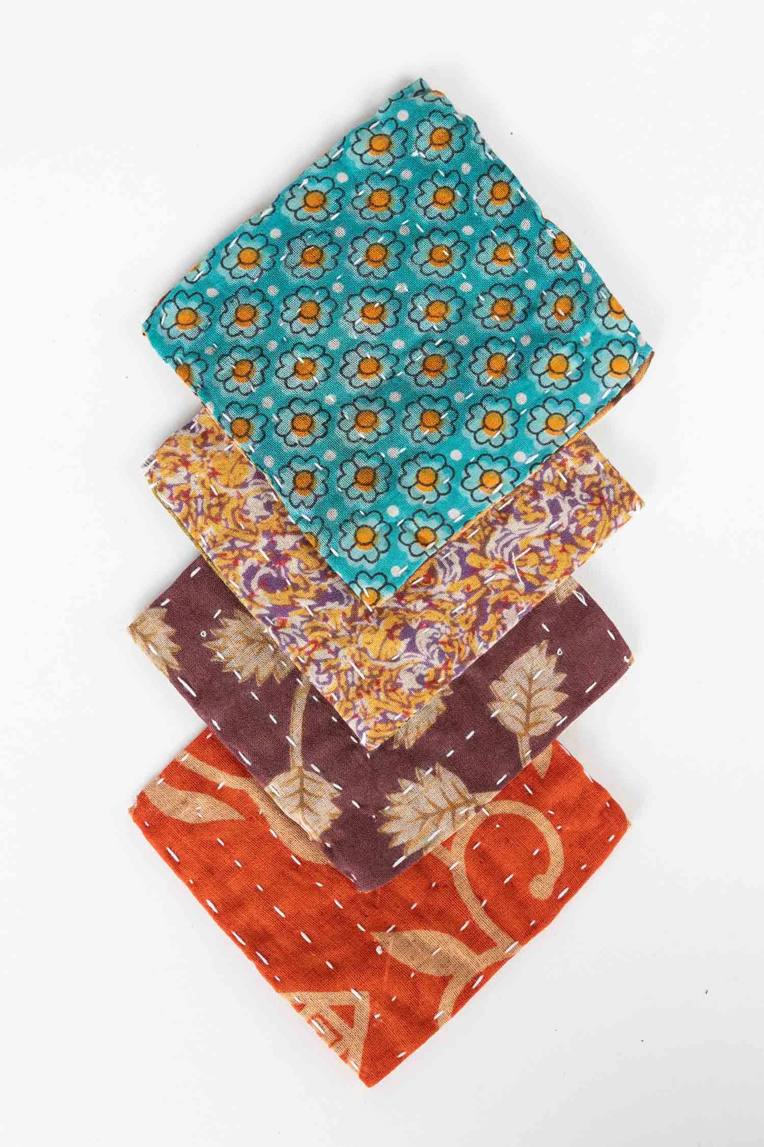 Reclaimed sari coasters in vibrant colors, stacked on a wooden table