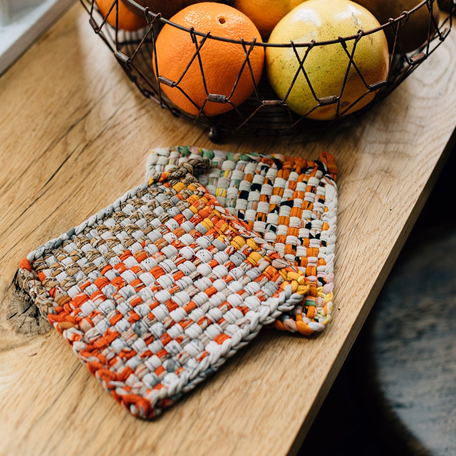 Colorful handmade hot mats displayed on a kitchen counter, showcasing their vibrant patterns.
