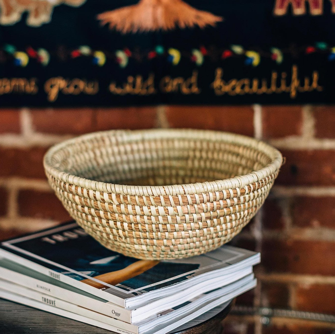 Top-down view of the handmade kaisa grass basket bowl on an entryway table with keys and coins inside