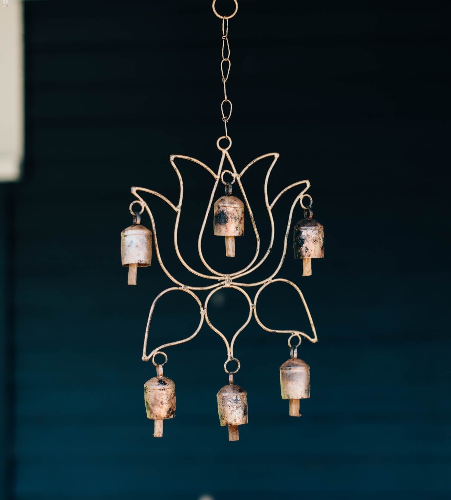 Tranquil Lotus Wind Chime hanging in a garden, showcasing its beautiful mango wood and iron bells.