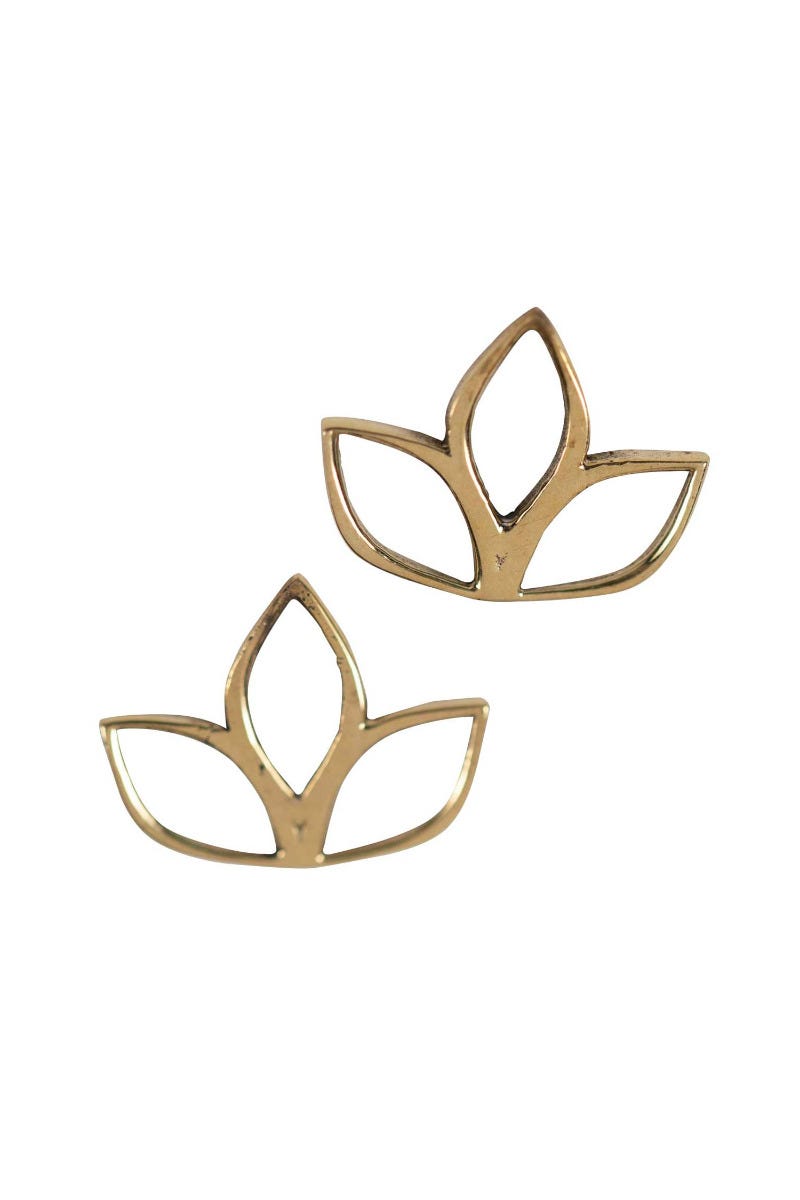 Close-up of lotus bloom artisan stud earrings on white cotton fabric, showing handcrafted petal details