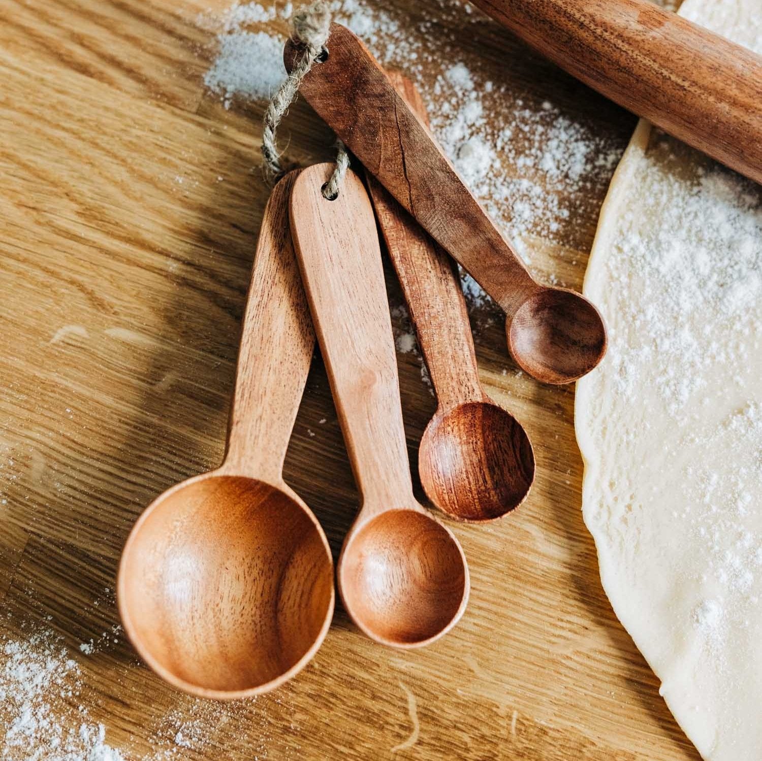 Hand-carved neem wood measuring spoons set displayed on a rustic kitchen countertop.