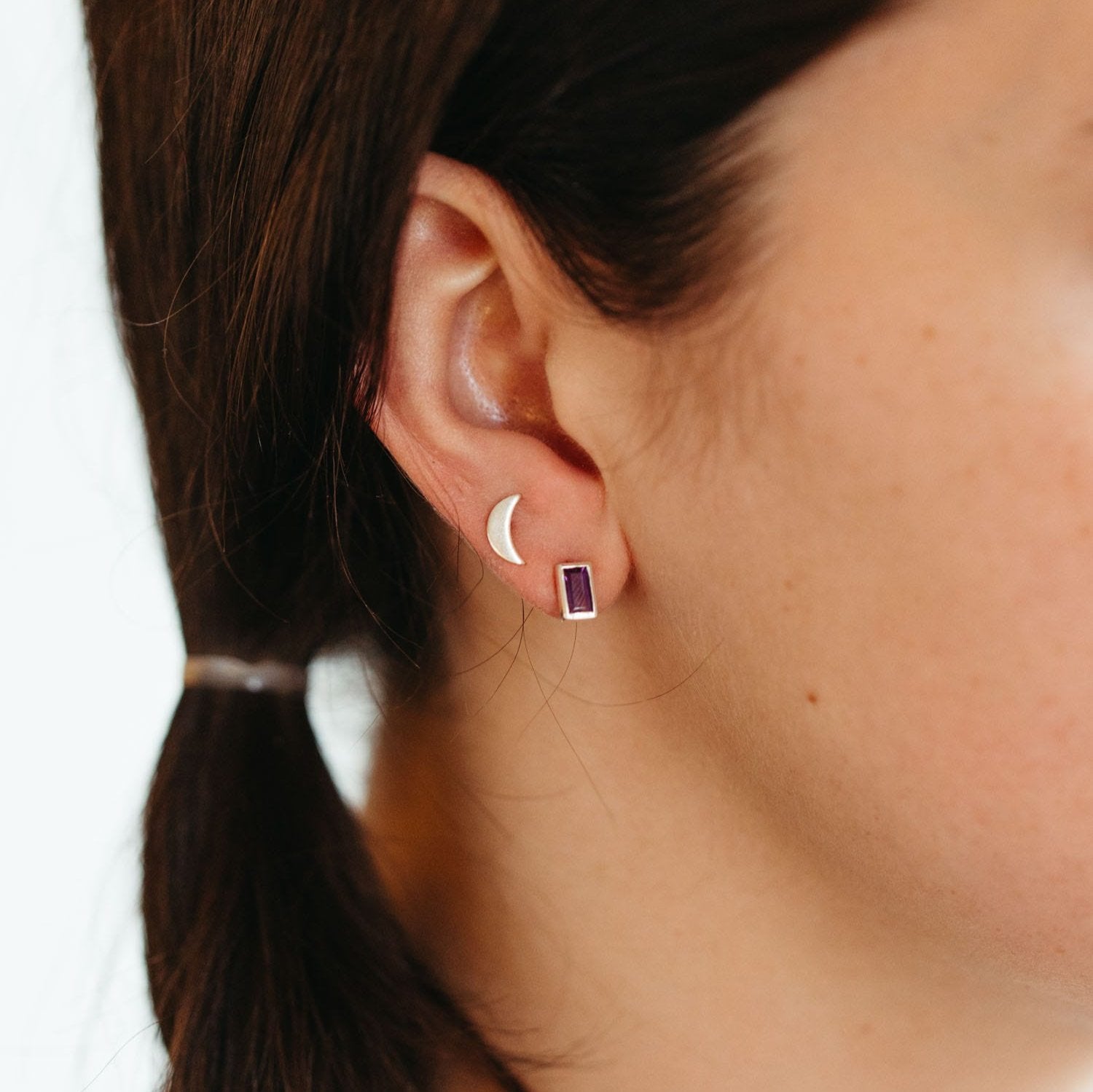 Close-up of handcrafted silver earrings with amethyst baguettes showing detailed craftsmanship