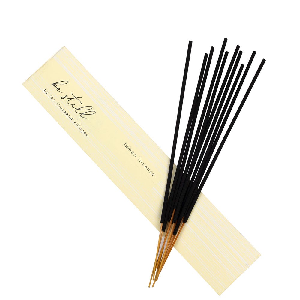 Close-up of lemon incense sticks arranged beside fresh lemon slices and tea tree leaves
