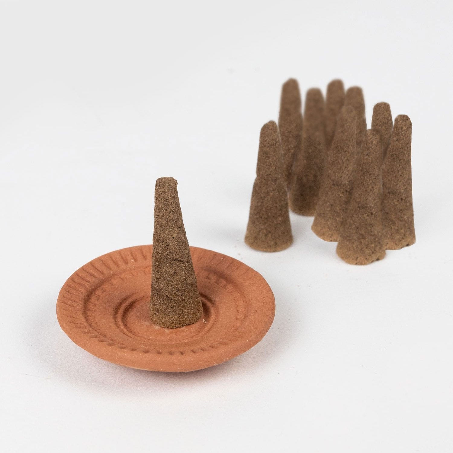 Serenity Sandalwood incense cones with a terracotta holder on display.