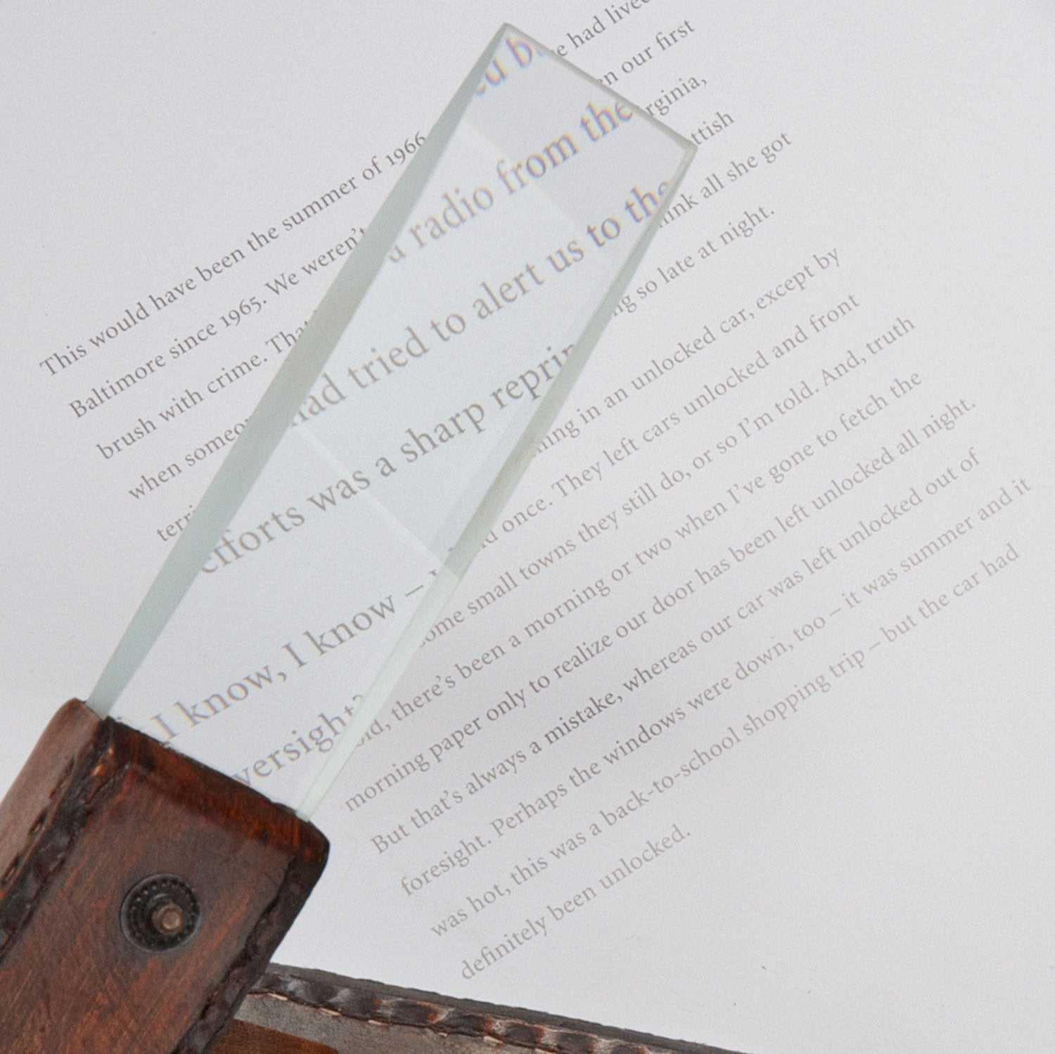 Close-up of square magnifying glass with leather handle resting on a newspaper