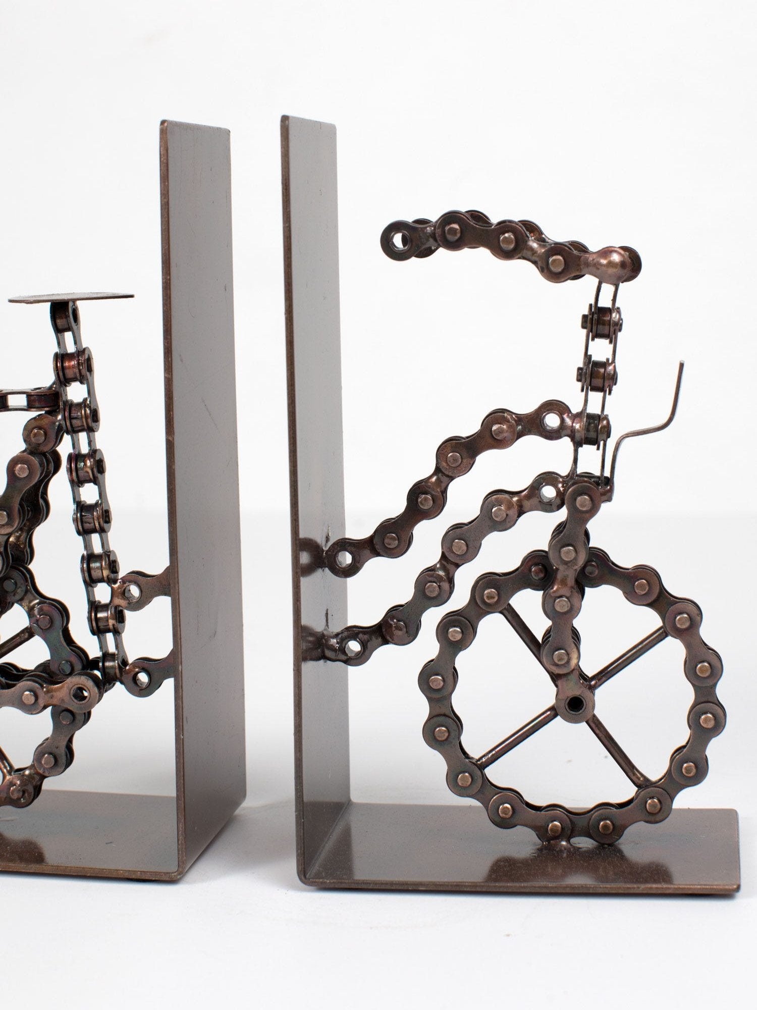 Handmade bicycle chain bookends displayed on a wooden shelf, showcasing their unique design.