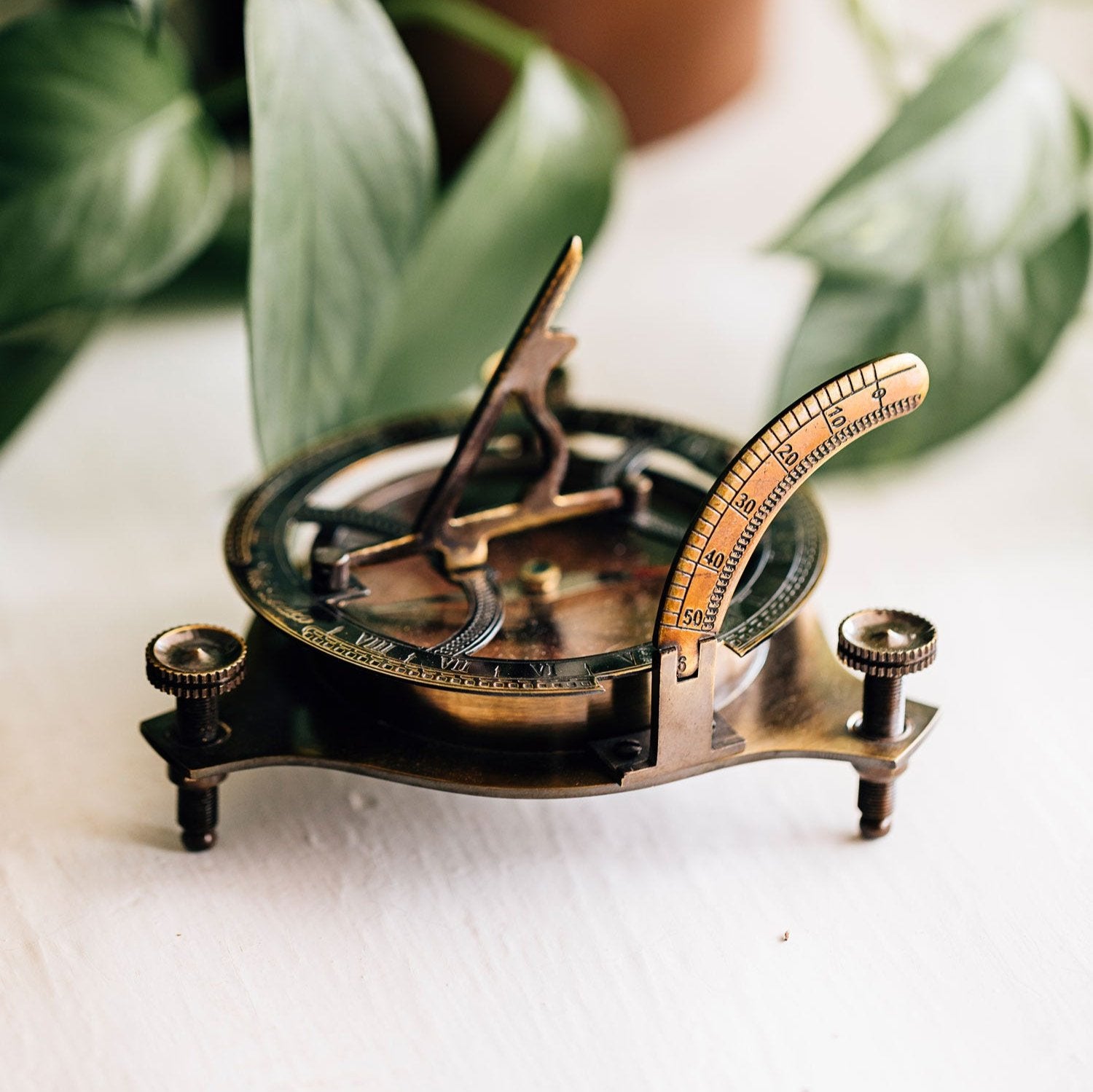 Top-down view of the brass sundial compass resting on vintage maps