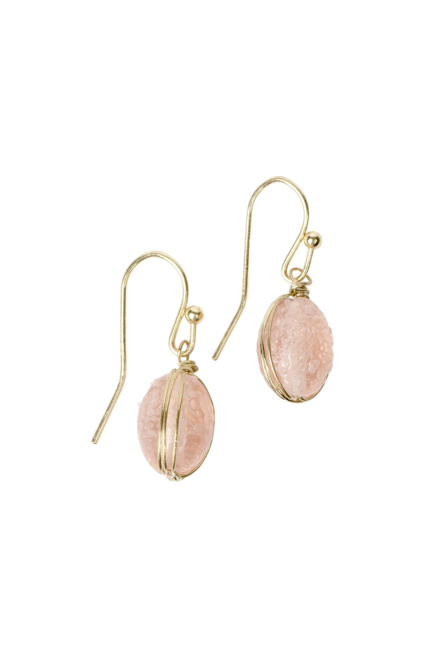 Elegant blush earrings displayed on a soft fabric background, showcasing their artisan craftsmanship.