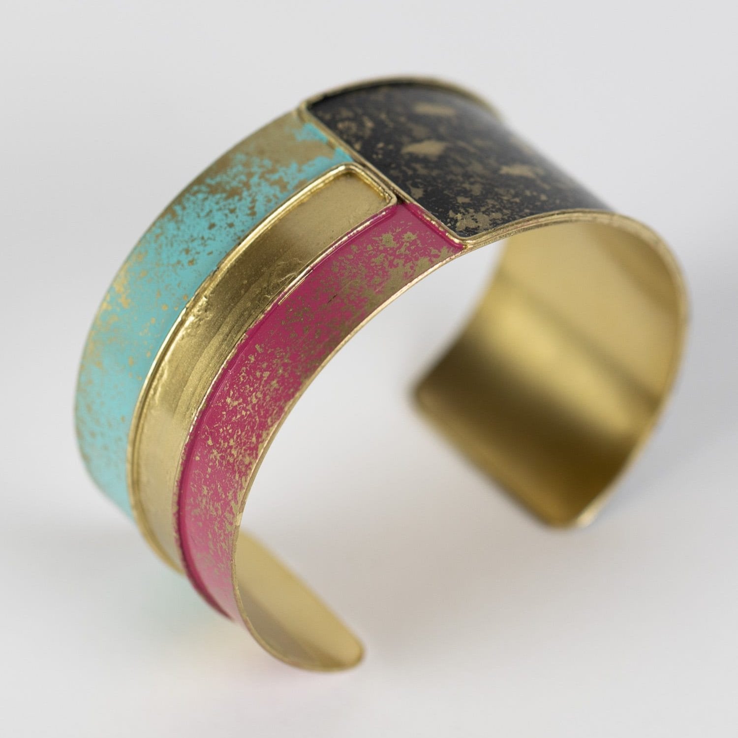 Close-up of bold enamel cuff bracelet with brass finish showing colorful design
