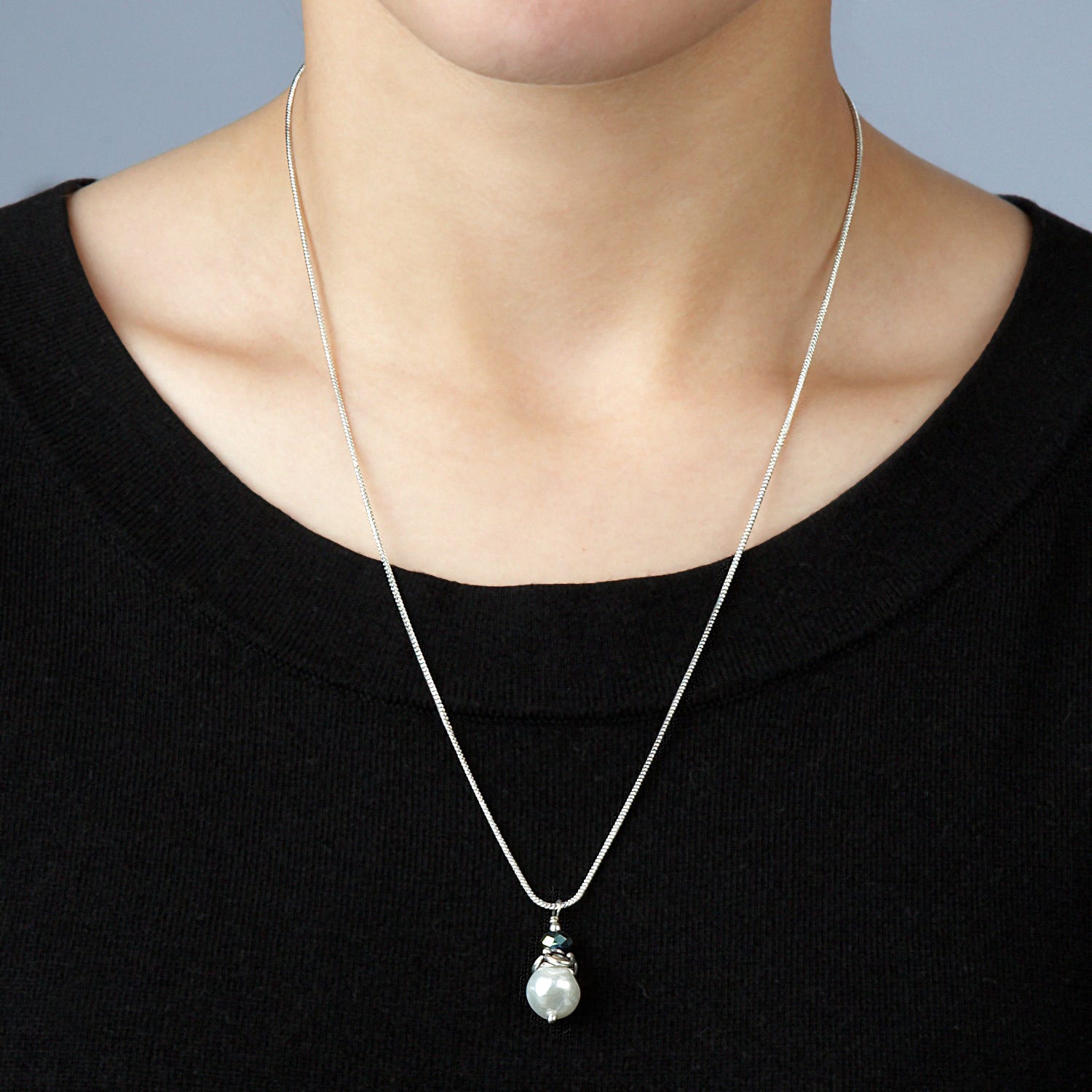 Close-up of the dainty pearl pendant necklace on a white background, highlighting its fine craftsmanship