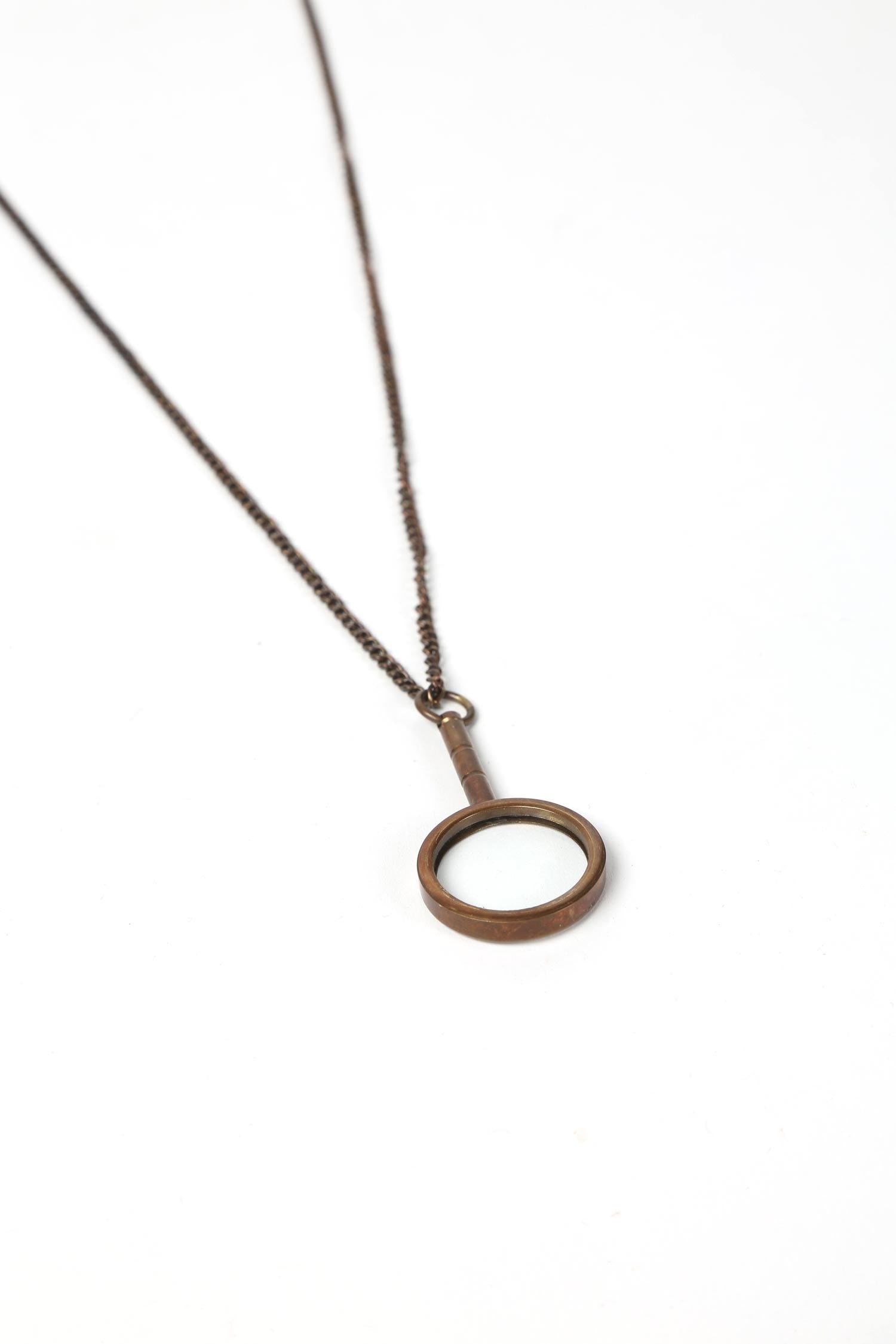 Close-up of handcrafted magnifying glass pendant necklace showing detailed artisan work