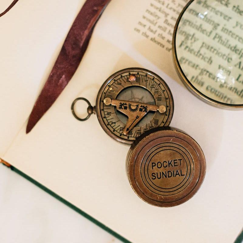 Close-up of brass pocket compass with gnomon and inscribed world time dial