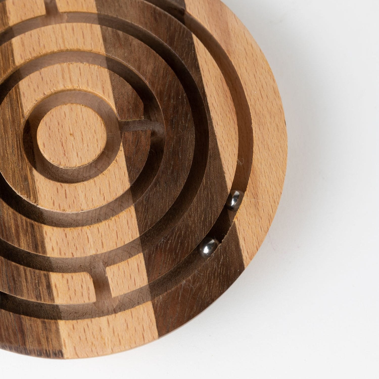 Close-up of handcrafted wooden maze game with silver balls for kids' educational play