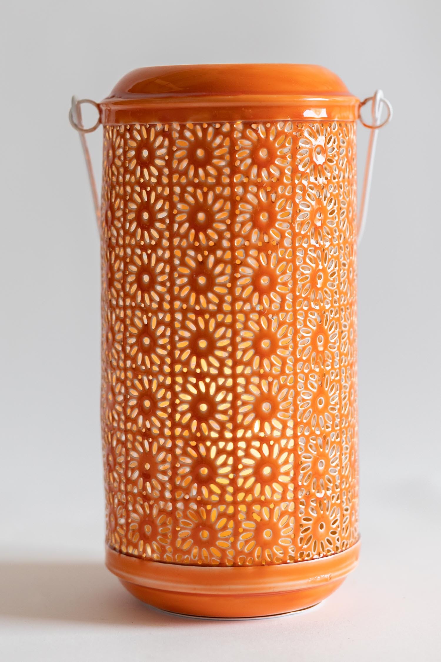 Enchanting artisan hanging candleholder showcasing vibrant orange enamel and gold interior from a side angle.