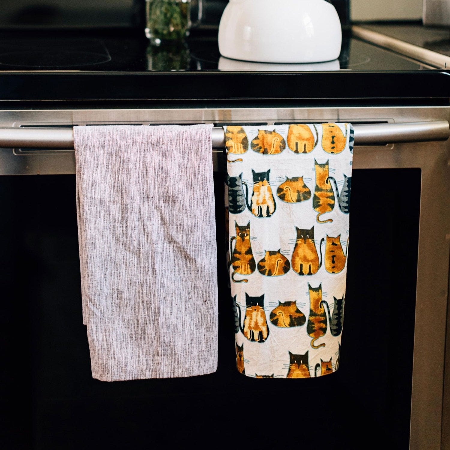 Cotton tea towel with playful cat print, perfect for kitchen use.