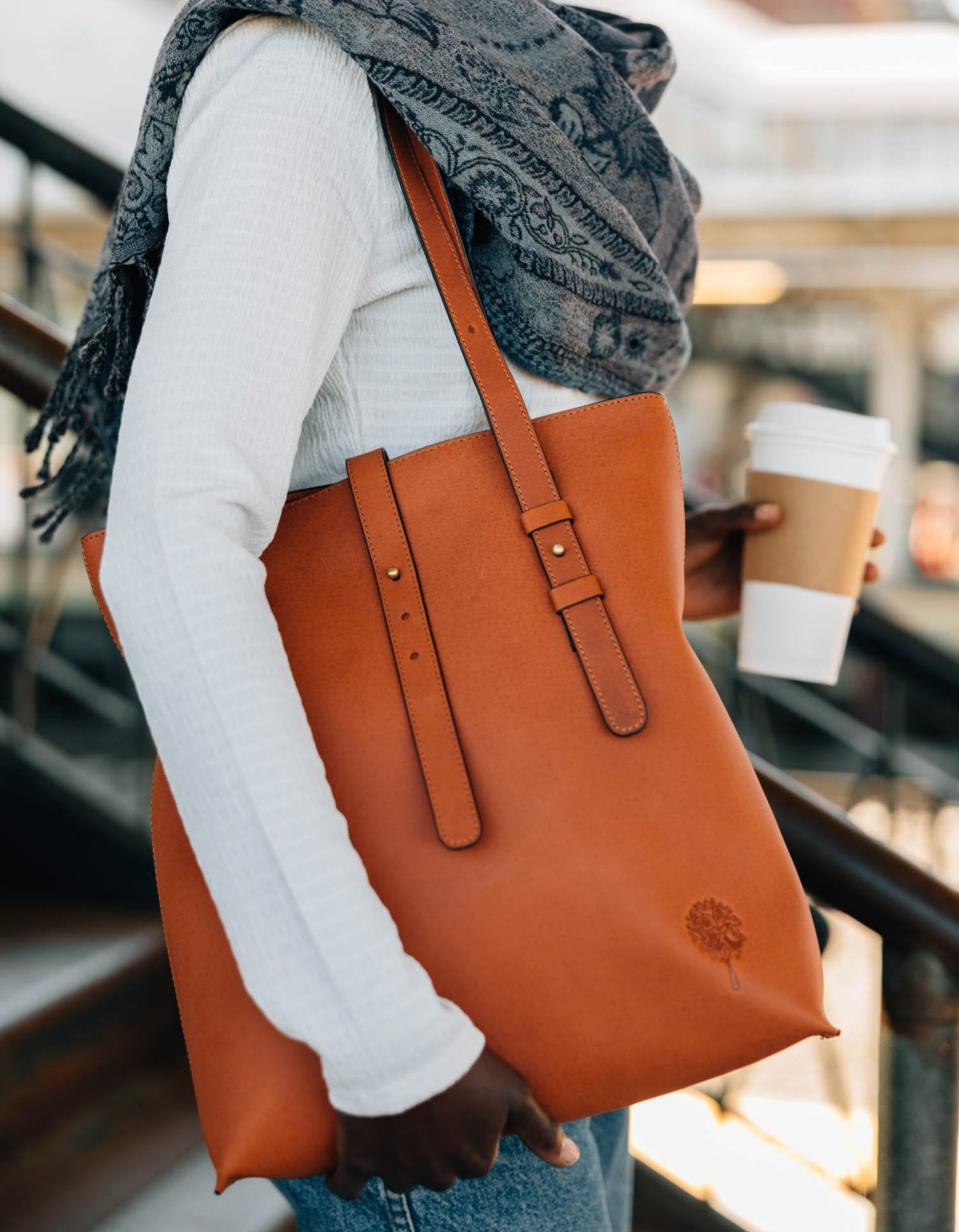 Close-up of cognac eco-leather shoulder bag showing adjustable strap and metal accents