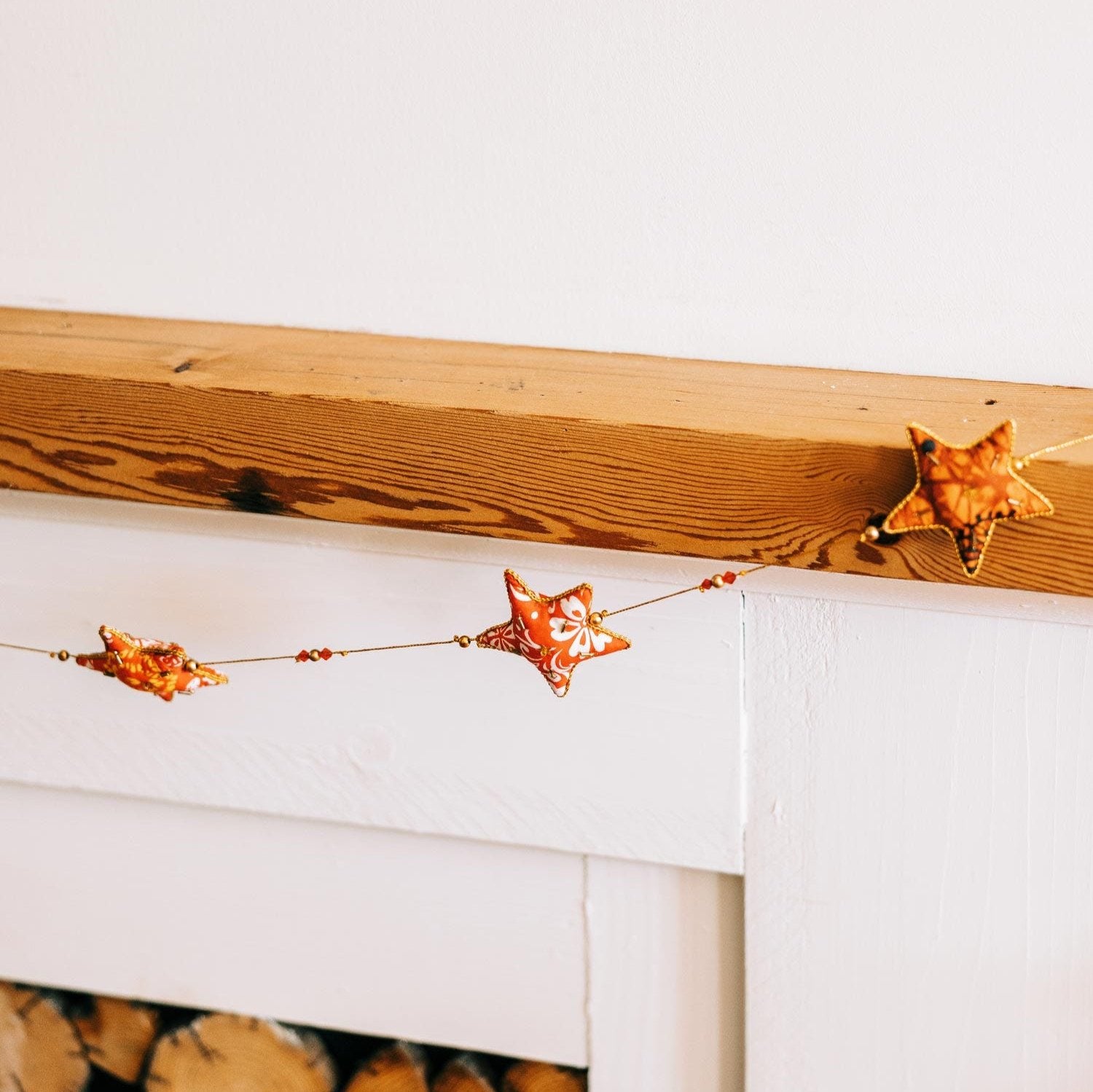 Close-up of snowy star garland with cotton stars in red, yellow, orange, and gold, ideal for Christmas decorations