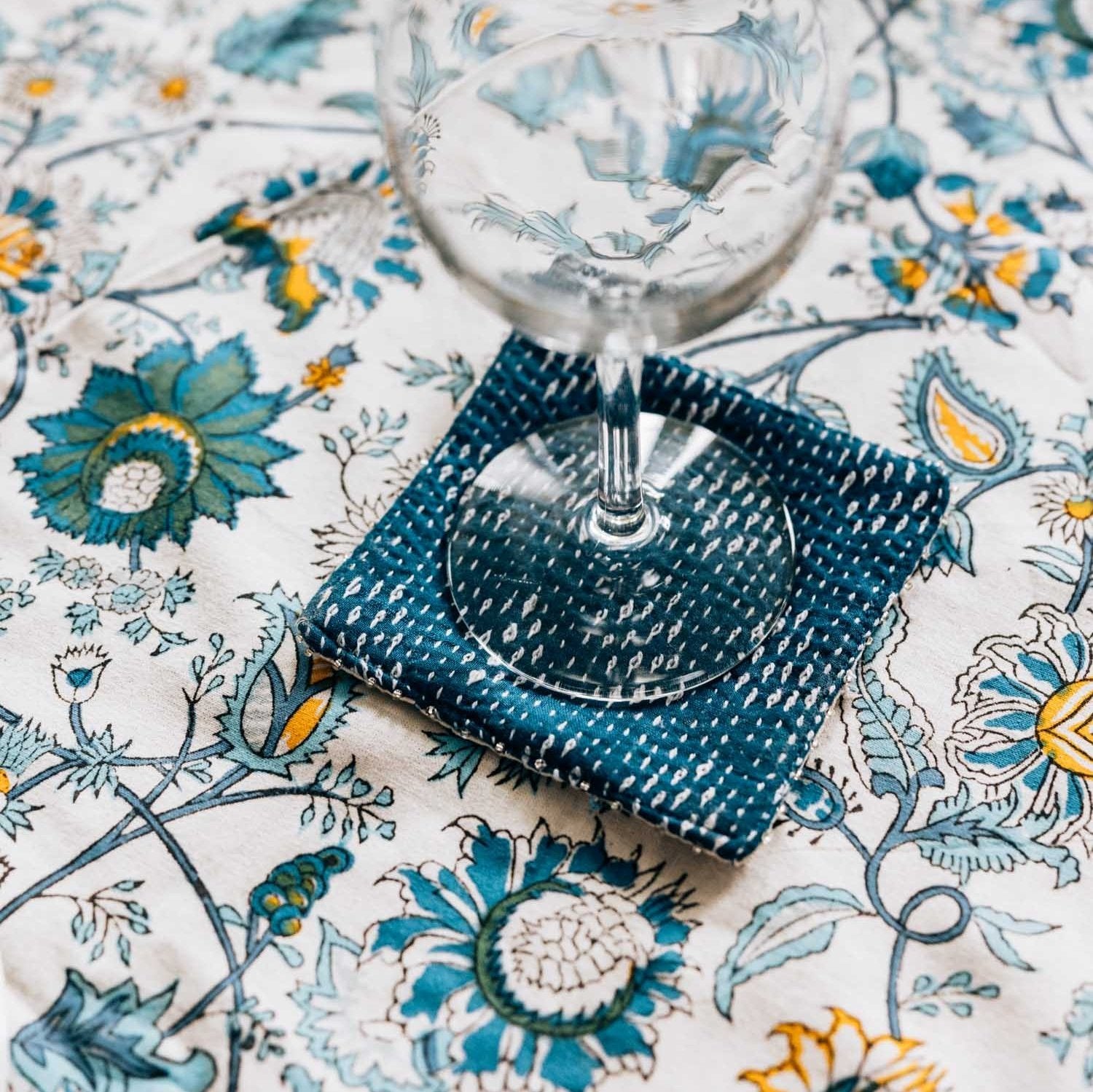 Top-down view of kantha coasters on a rustic wooden table, showcasing colorful stitching and boho charm