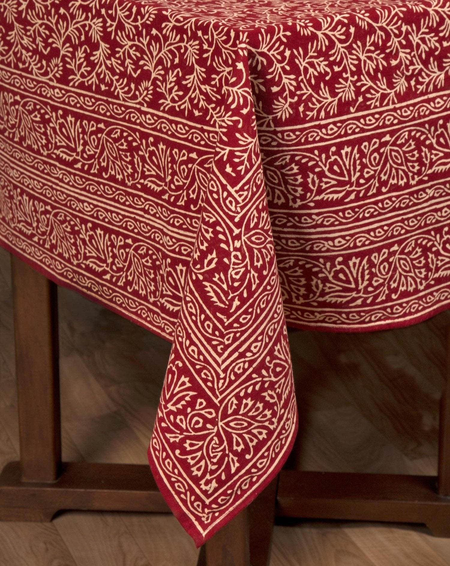 Top-angle view of block print tablecloth showcasing red vine motifs across 100% cotton weave